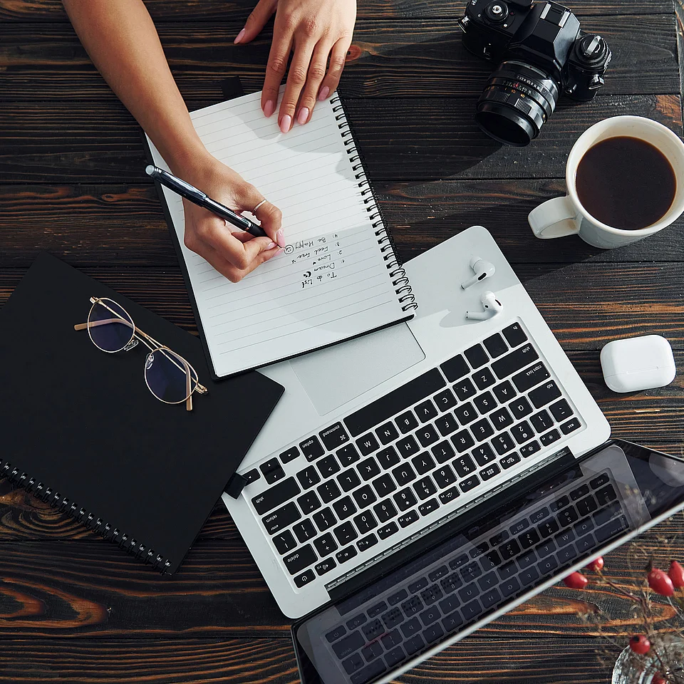 Arbeitsplatz mit Notizbuch, Laptop und Kaffee